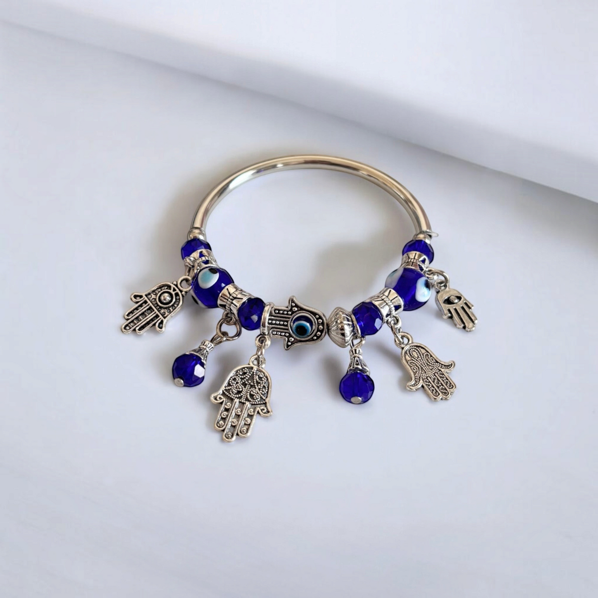 Omayra Boutique bohemian alloy bracelet featuring blue glass evil eye beads and silver hamsa hand charms.