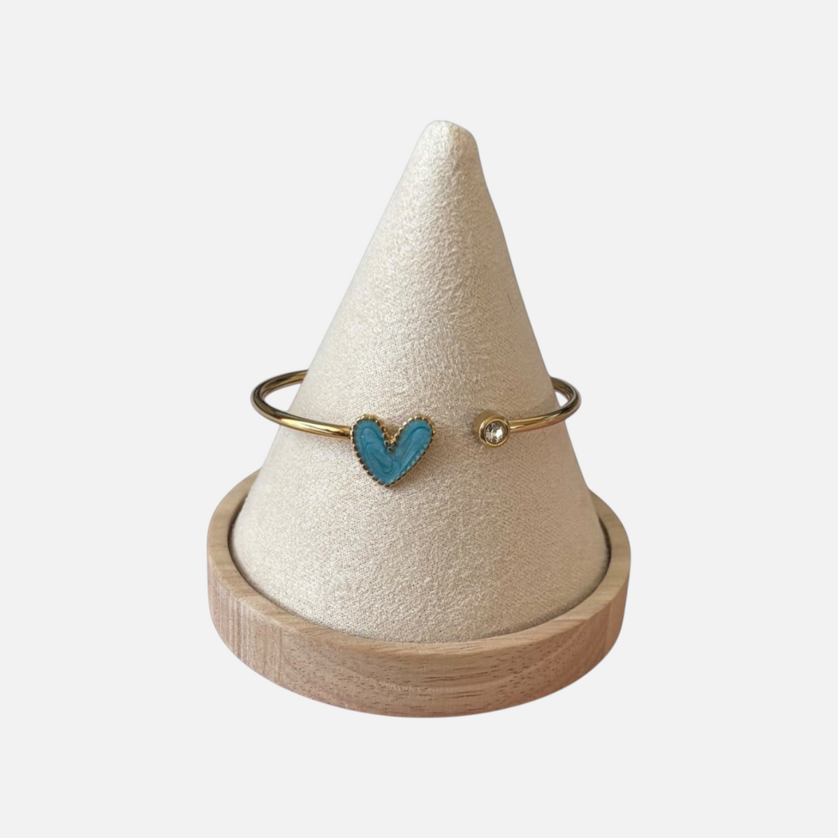 Omayra Boutique stainless steel cuff bracelet with a blue heart charm and a sparkling gem on a beige display cone.