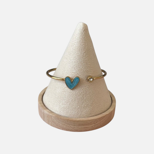 Omayra Boutique stainless steel cuff bracelet with a blue heart charm and a sparkling gem on a beige display cone.