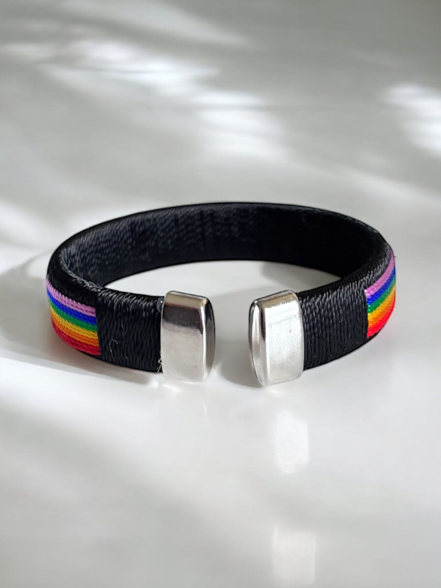 Brazalete abierto con dijes y cuerdas de arcoíris