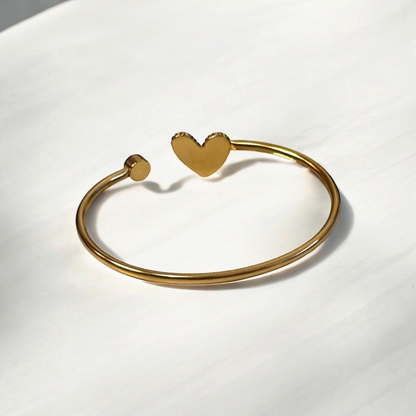 Omayra Boutique gold-tone stainless steel cuff bracelet featuring a heart charm and a small round stud detail.