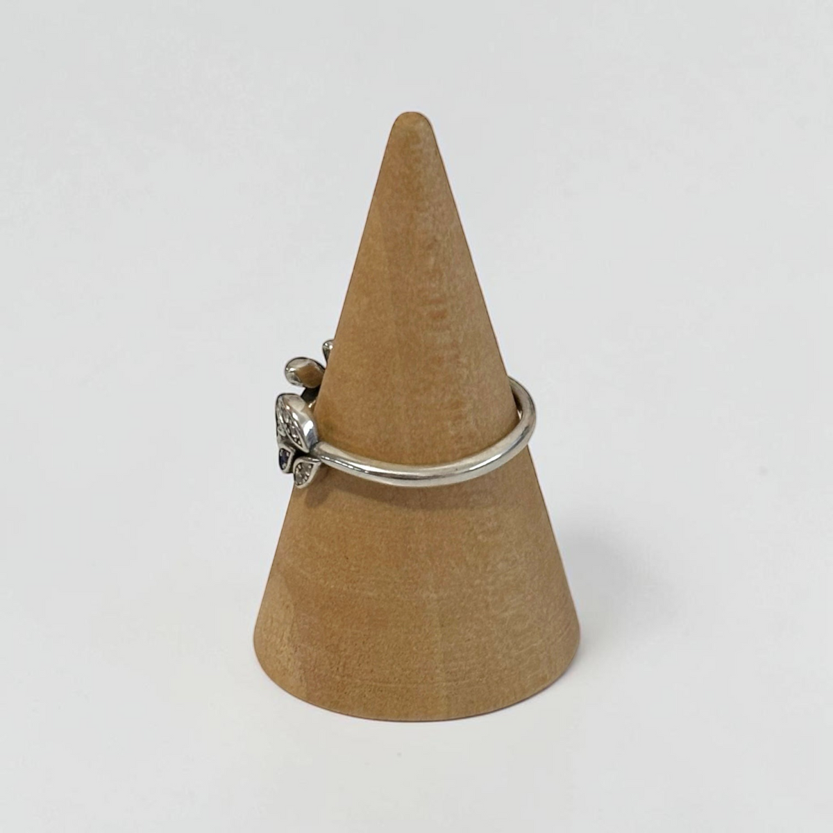 Omayra Boutique 925 sterling silver adjustable ring with a blue and clear zircon leaf design on a wooden cone stand.