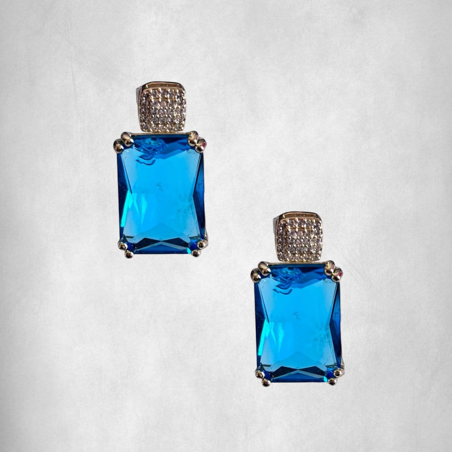 Omayra Boutique Blue Princess Drop Earrings with blue cubic zirconia and light gold setting. Classic 1 inch drop earrings.