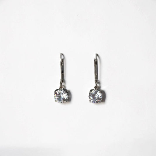 Omayra Boutique silver dangle earrings with sparkling cubic zirconia stones displayed on a white arch stand.