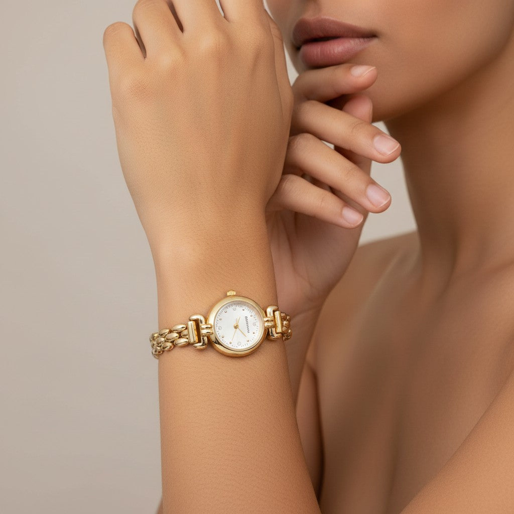 Omayra Boutique polished gold-tone box chain watch with a compact round dial and delicate stone markers on a wrist.