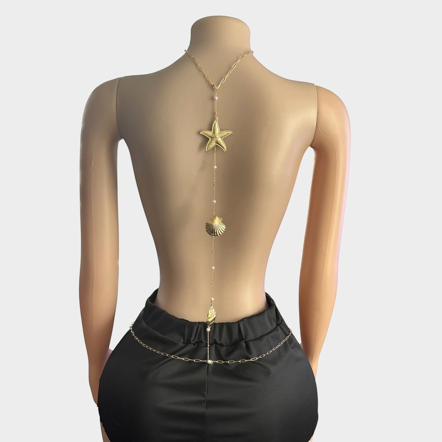 Omayra Boutique gold-tone back body chain featuring starfish, seashell charms, and faux pearls on a mannequin.