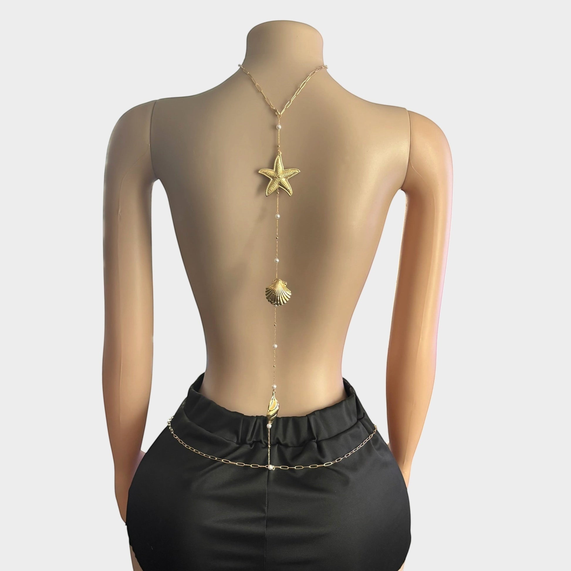 Omayra Boutique gold-tone back body chain featuring starfish, seashell charms, and faux pearls on a mannequin.
