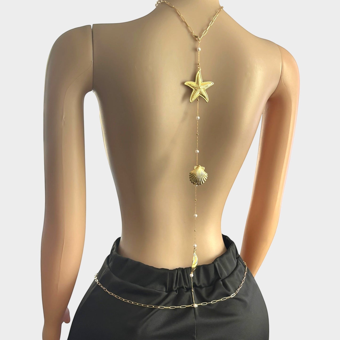 Omayra Boutique gold-tone back body chain featuring starfish, seashell charms, and faux pearls on a mannequin.