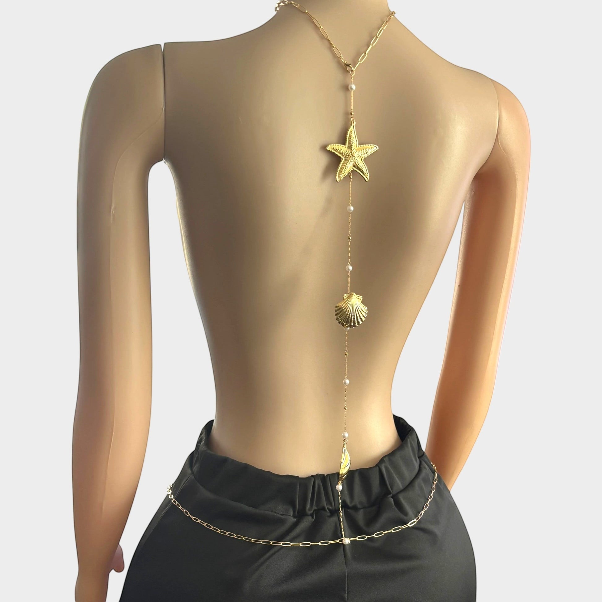 Omayra Boutique gold-tone back body chain featuring starfish, seashell charms, and faux pearls on a mannequin.