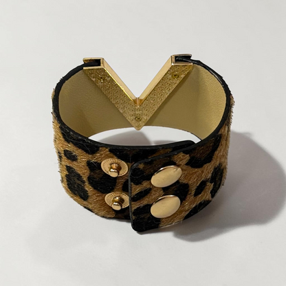 Omayra Boutique leopard print leather cuff bracelet with a gold V-shaped charm and double snap button closure.