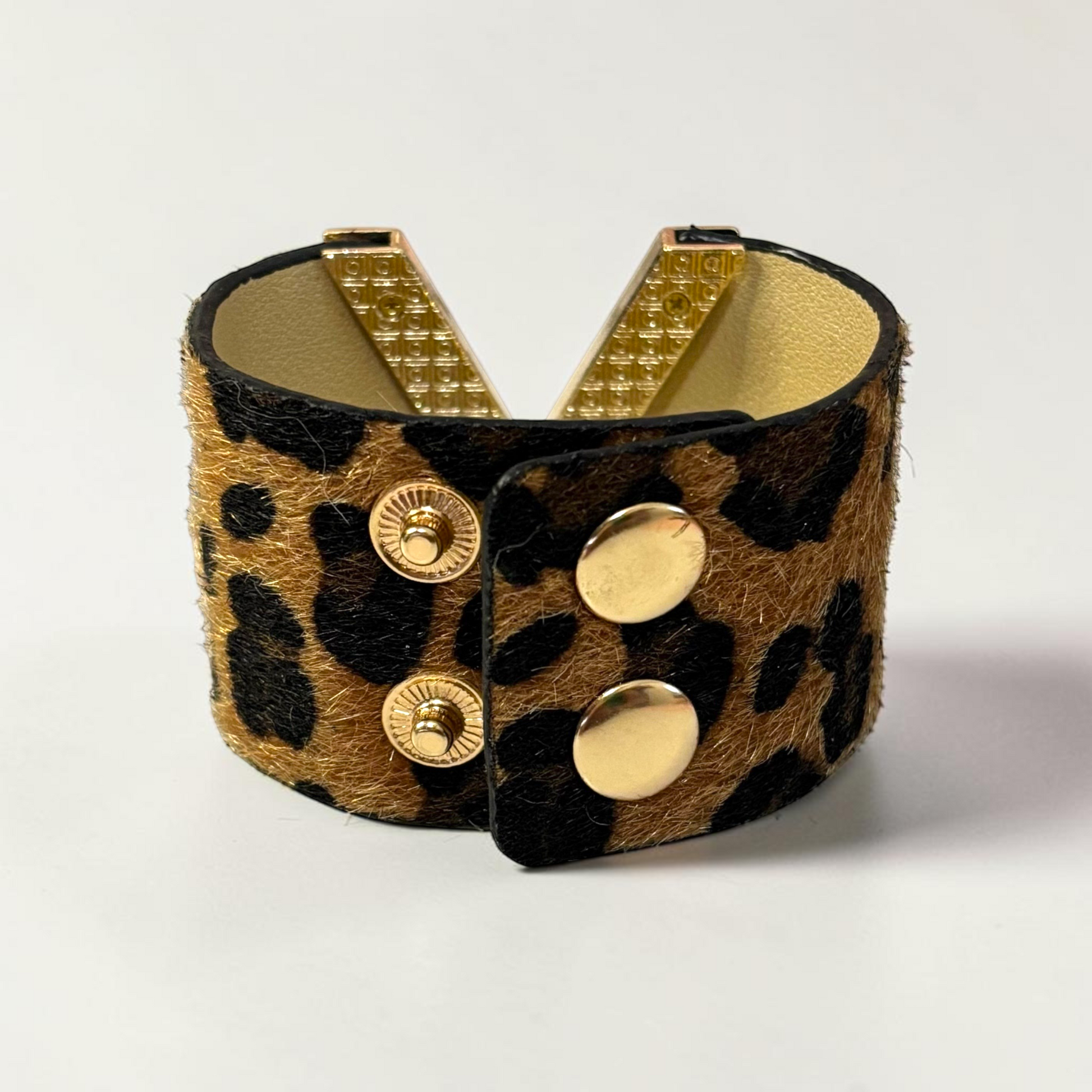 Omayra Boutique leopard print leather cuff bracelet with a gold V-shaped charm and double snap button closure.