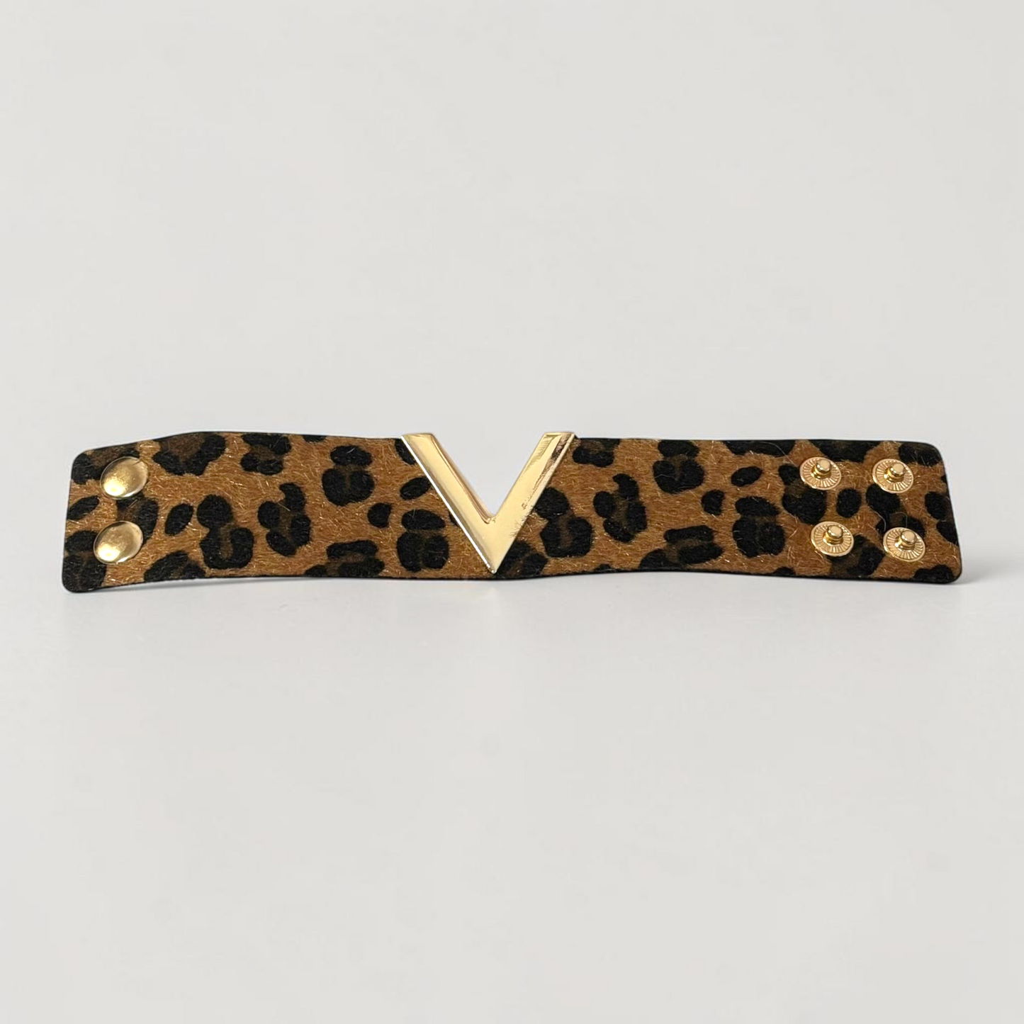 Omayra Boutique brown leopard print leather cuff bracelet with a gold V-shaped charm and double snap closure.