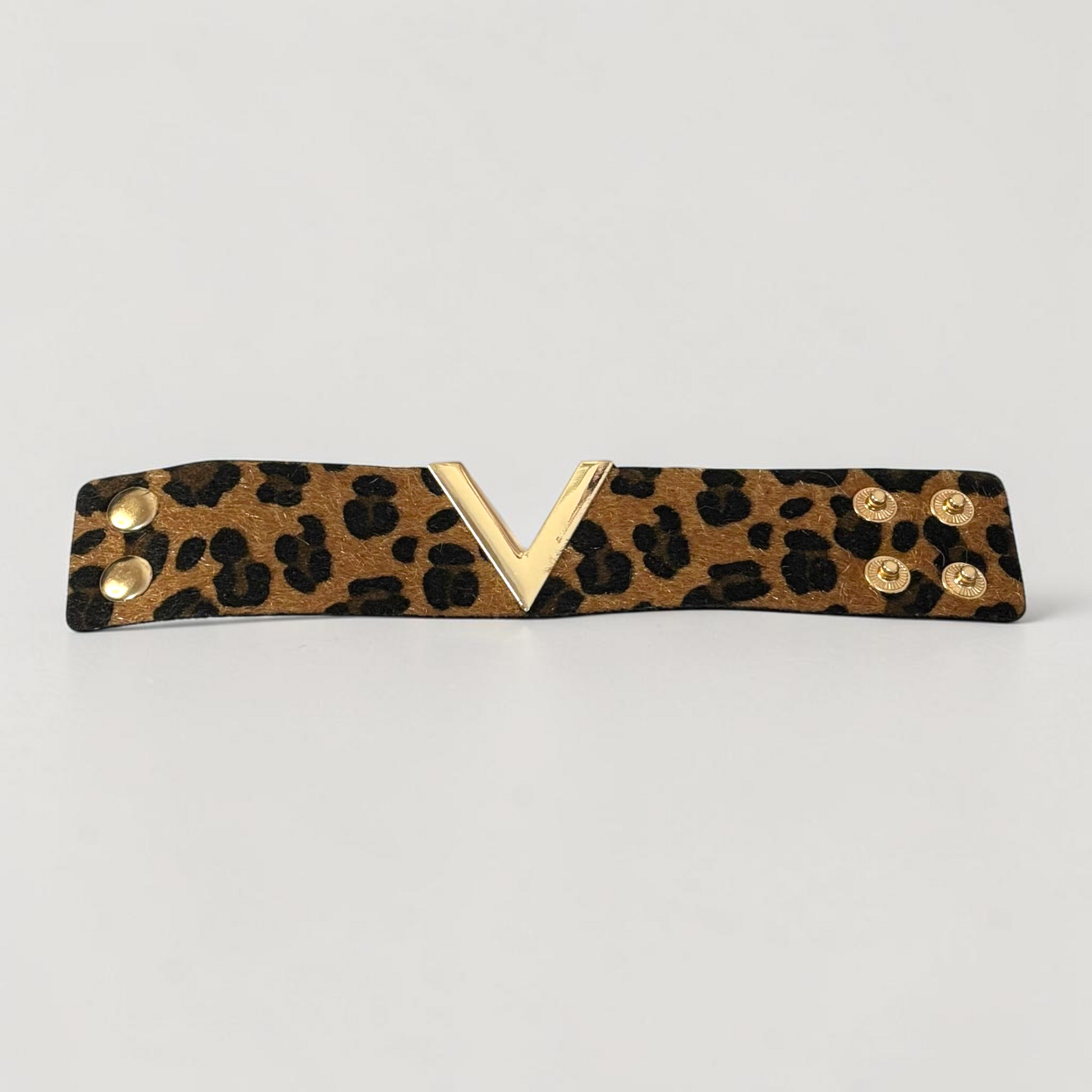 Omayra Boutique brown leopard print leather cuff bracelet with a gold V-shaped charm and double snap closure.