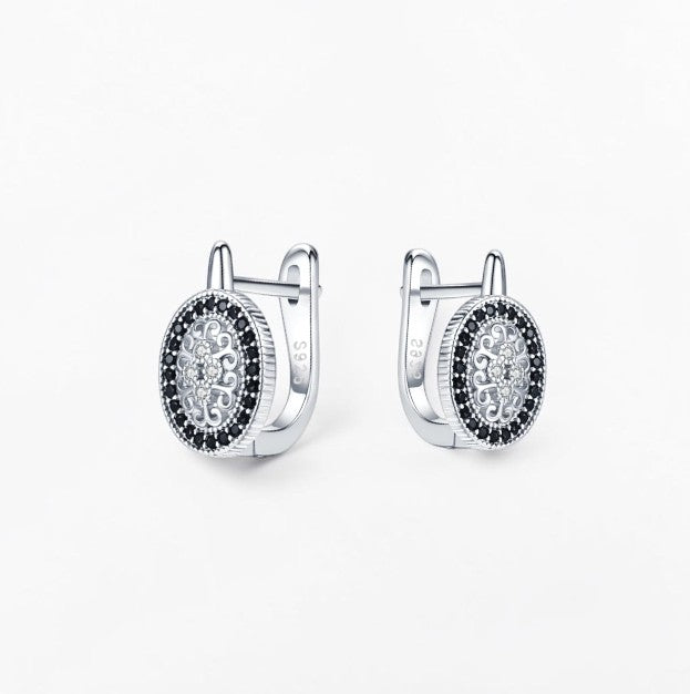 Omayra Boutique oval hoop earrings in 925 silver featuring intricate filigree patterns and black spinel stones.