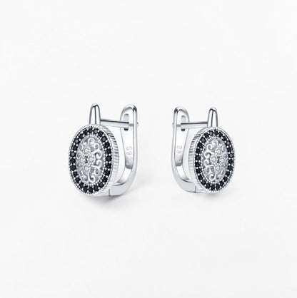 Omayra Boutique oval hoop earrings in 925 silver featuring intricate filigree patterns and black spinel stones.