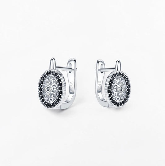 Omayra Boutique oval hoop earrings in 925 silver featuring intricate filigree patterns and black spinel stones.